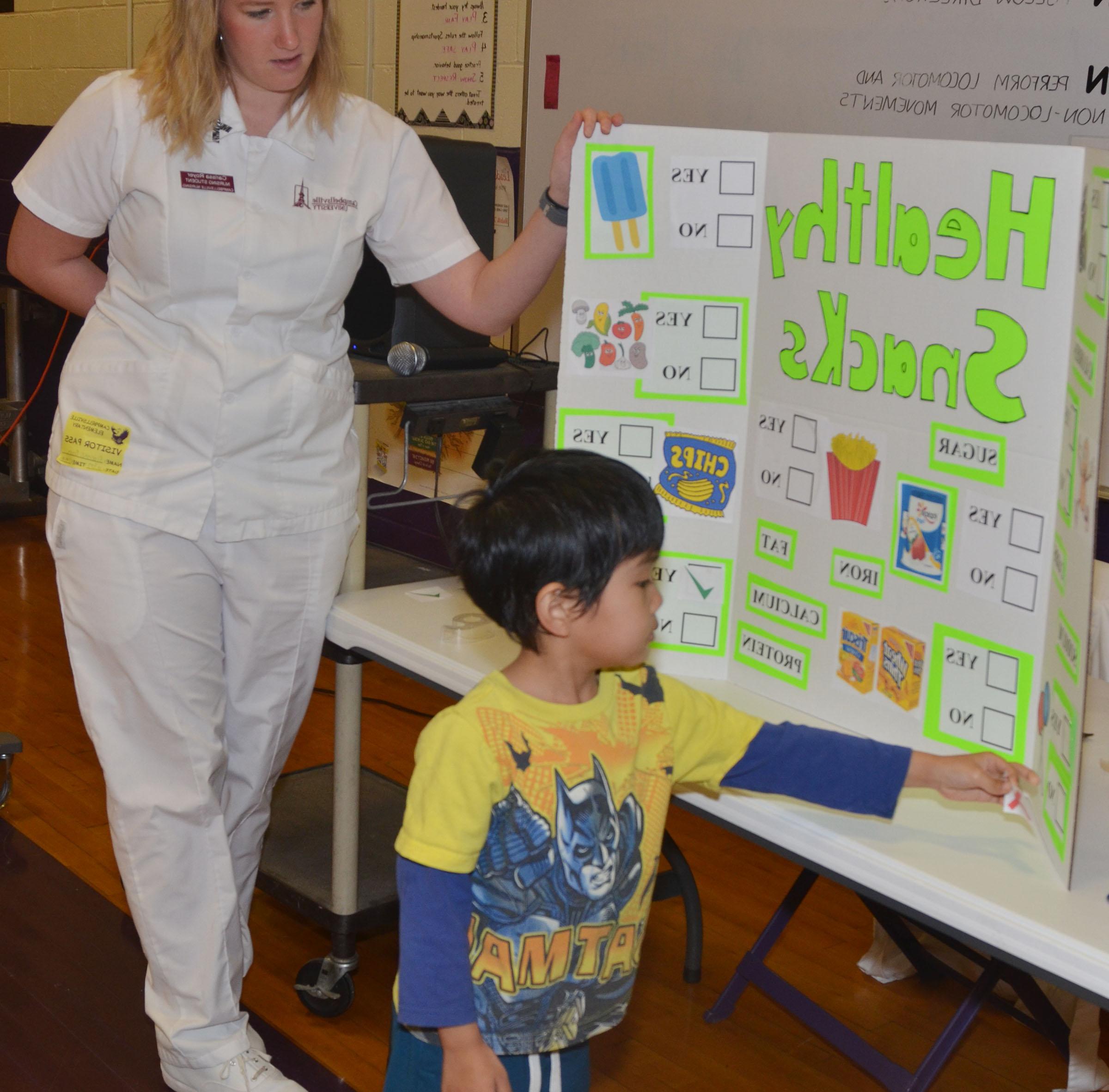 CU nursing student Carissa Royer asks CES kindergartner Zach Hak to choose a not so healthy snack.