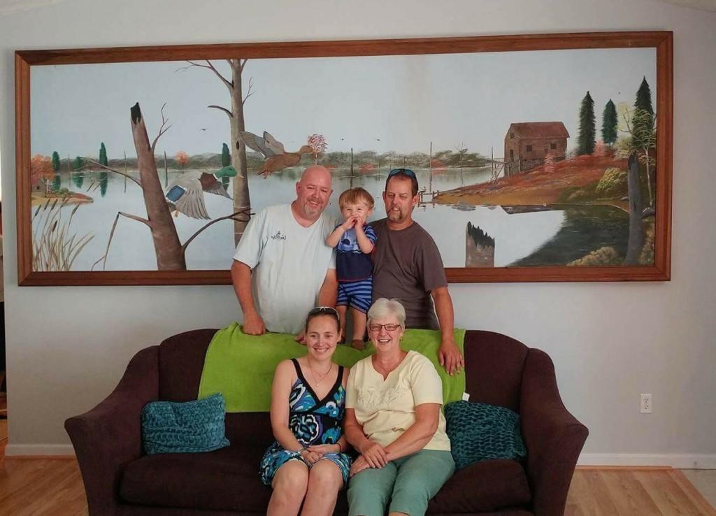 Seated in Myna Graham’s home, with the painting her husband painted now in their home. From left are: Front row -- Myna Graham; Victoria Graham, Jerry’s daughter-in-law, married to Michael. Back row: Michael Graham, Jerry’s son; Lucas Graham, Michael’s son; and Jerry Keith Graham, Jerry’s oldest son. Keith lives in Nicholasville, Ky., and made preps for the installation and helped put the painting in their house. (Campbellsville University Photo by Jesse Harp)